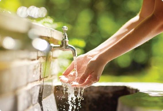 a hand pouring water from a faucet