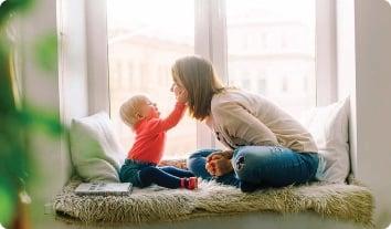 a person and a baby sitting on a bed