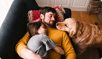 a person and a child sitting on a couch with a dog