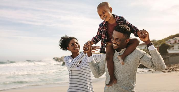 a person carrying a child on the shoulders on a beach