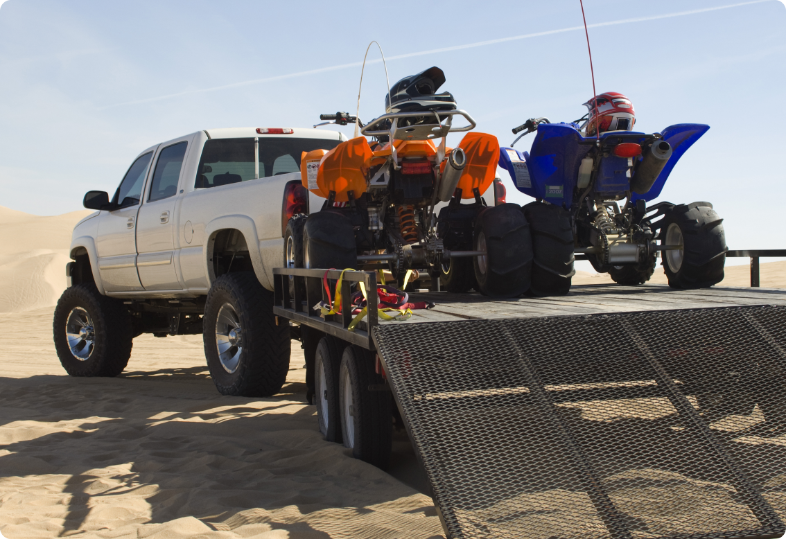 A truck with trailer carrying a couple of ATVs