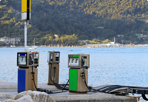 a row of gas pumps on a dock by a body of water