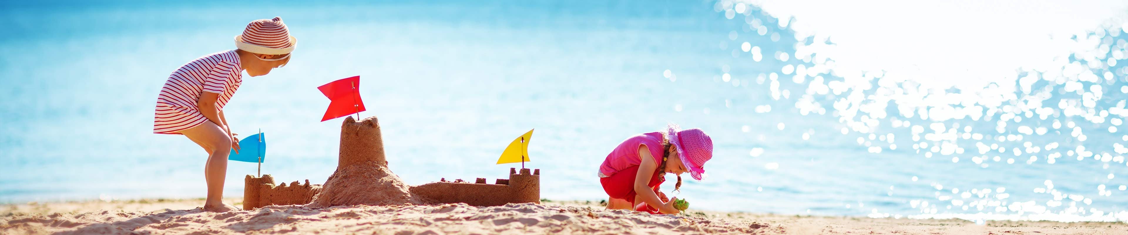 Image of two children playing at the beach on a sunny day.